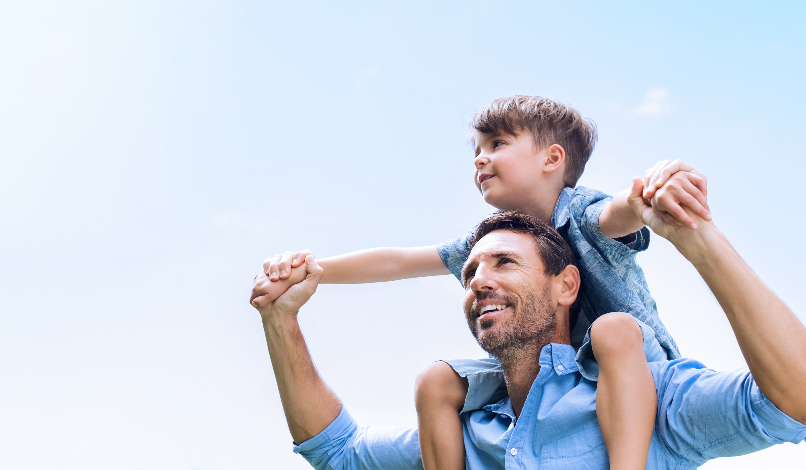 barn som sitter på en mans axlar.